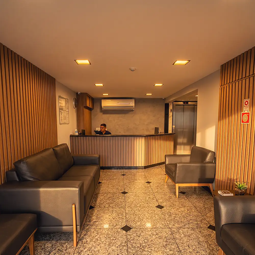 Recepção do Hotel Rinkão em Cachoeiro de Itapemirim, com balcão de atendimento, sofás e elevador